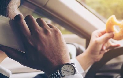 Man eating and using the phone while driving.