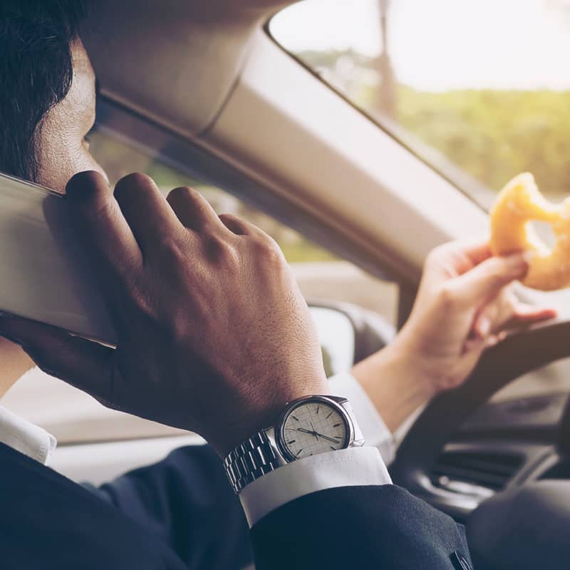 Man eating and using the phone while driving.