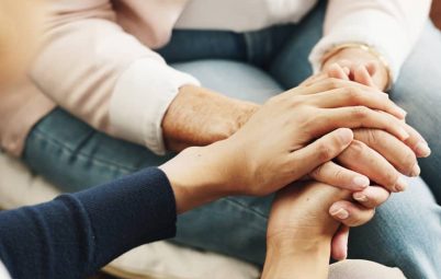 A person holding hands and comforting another person.