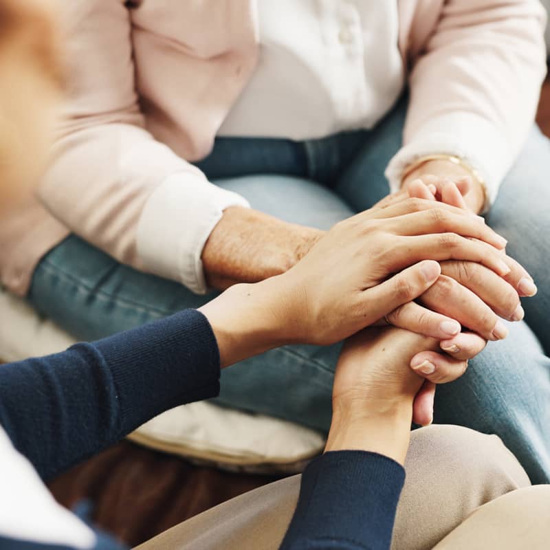 A person holding hands and comforting another person.