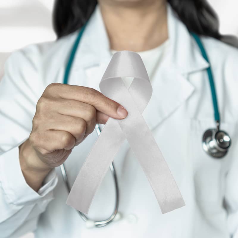 A female doctor holding up a ribbon to show support for lung cancer.